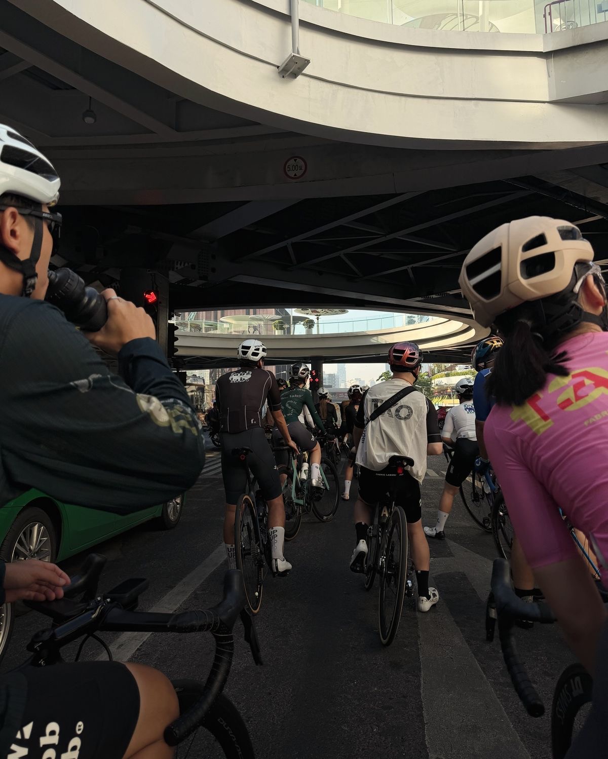 Cyclists gathered beneath an urban overpass